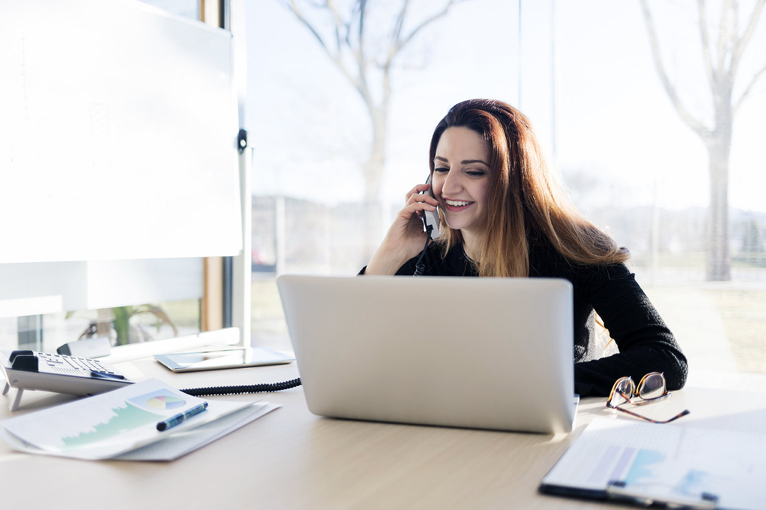 Woman talking on the phone and using laptop computer